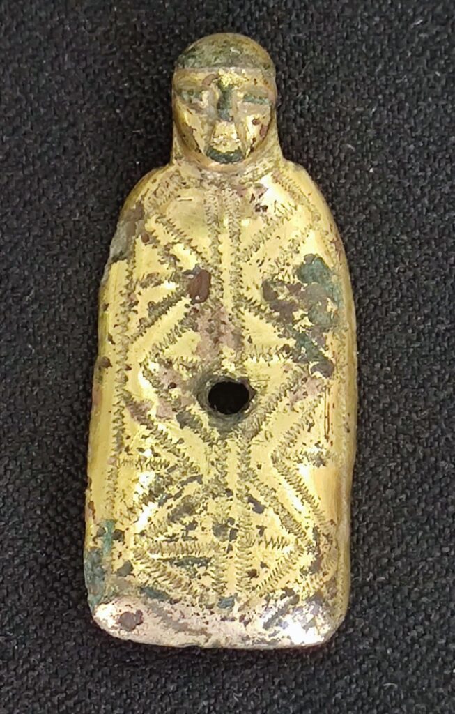 Archaeologists have begun excavating the remains of a medieval church near Kiskunlacháza, Hungary, years after traces of the building were first identified during field surveys.

The site came to attention when museum volunteers walking near the Dömsöd–Arapasztó channel found human skull fragments brought to the surface by plowing. Stones and construction debris scattered across the field suggested that a demolished church and its cemetery lay beneath the farmland.

Researchers believe the ruins belonged to the church of the medieval settlement of Szentiván. The building is thought to have been dedicated to Saint John the Baptist.

A Gilded Find East of the Church

Shortly before excavations began, a metal-detector survey uncovered a small fire-gilded religious figure east of the church site. Archaeologists believe it may once have formed part of a processional cross carried during Christian ceremonies.

The object’s exact date and original position on the cross have not yet been established. Its discovery, however, adds a rare religious artifact to the evidence emerging from the site.

The excavation began after years of preparation and survey work. The team is working through intense summer heat, dust and storms to expose the surviving remains of the church and learn more about the medieval community that once lived around it.

The project brings together archaeologists from Pázmány Péter Catholic University and Eötvös Loránd University, staff from the Ferenczy Museum Centre, community archaeology volunteers and residents of Kiskunlacháza.