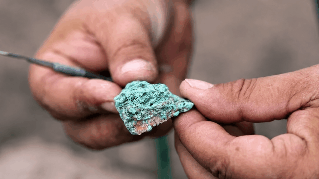 A researcher examines a green malachite fragment recovered from Çayönü Tepesi.