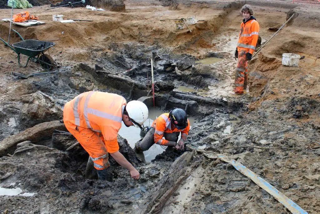 Archaeologists excavating preserved timbers in a Bronze Age waterhole in England