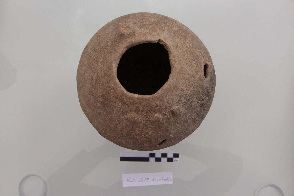 Top view of a round brown Hittite vessel with a wide central opening