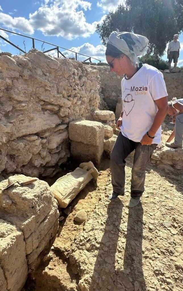 Archaeologist Paola Sconzo standing beside the newly uncovered marble statue at Mozia.