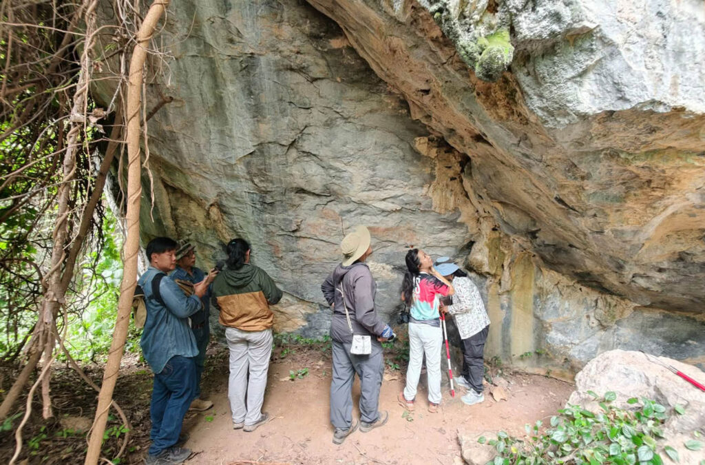 Archaeologists examining prehistoric rock paintings at Pha Wiang Cave in Thailand
