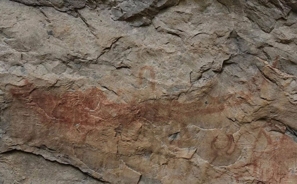 Overlapping red animal figures and abstract patterns at Pha Wiang Cave in Thailand