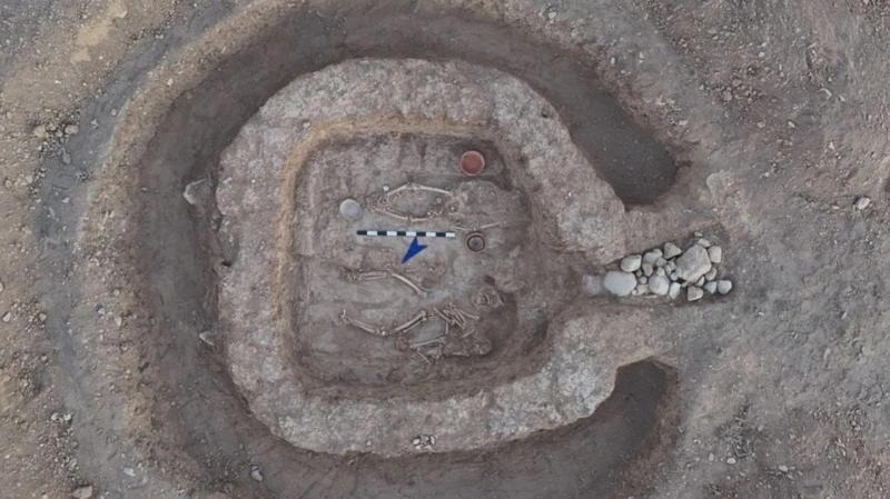 Overhead view of an excavated burial structure with human remains and pottery in southern Kazakhstan.