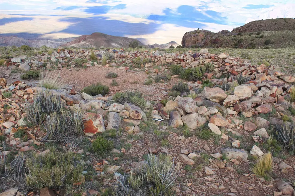 Low stone walls and a passage among rocks and shrubs at the Mendoza mountain site.