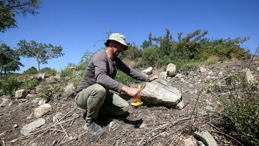 Archaeologist documents a carved stone at Hadrianoi in Bursa, Türkiye