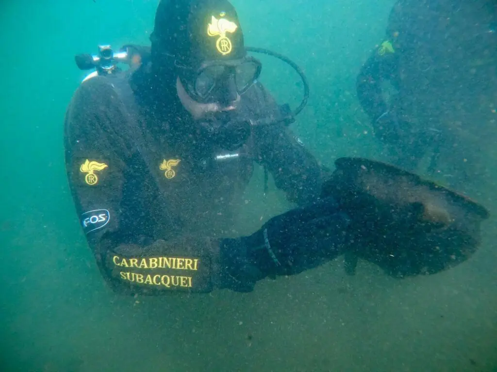 Carabinieri diver holding the Bronze Age sword underwater during its recovery from Lake Mezzano.