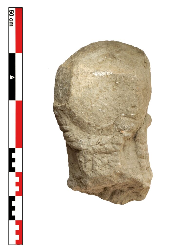 Side view of the limestone statue head with its preserved braided hairstyle