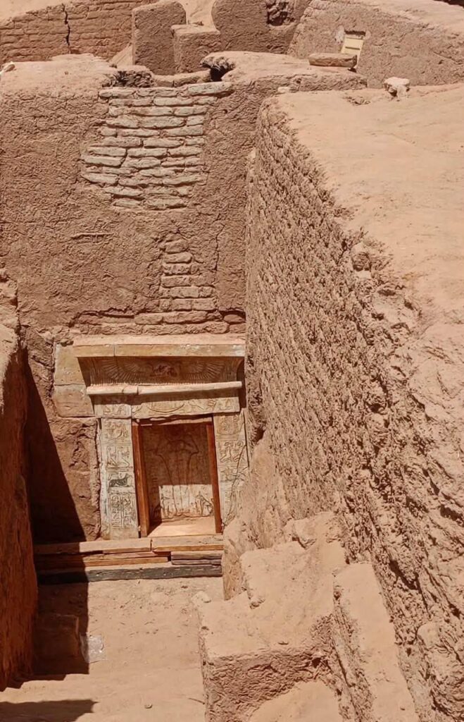 Steps leading down to the decorated stone entrance of a Roman-era tomb at Bir al-Shaghala, Egypt.