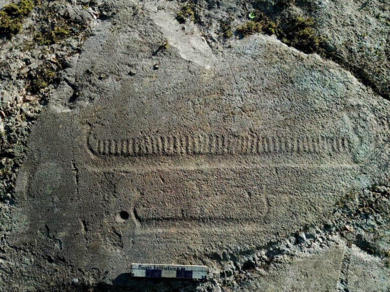 Ship carving on a granite rock surface at Trättelanda, Sweden, with a measuring scale below it.