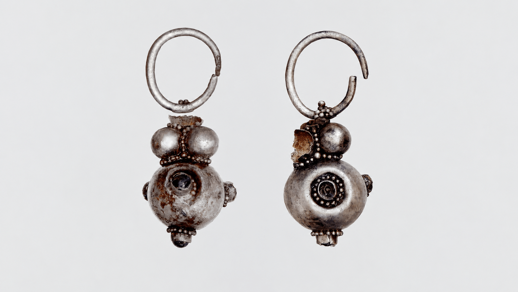 Restored silver Avar earrings with spherical pendants from a 1,400-year-old grave in Hungary.