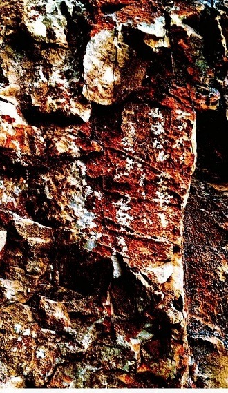 Close-up of a heavily weathered three-line Pahlavi funerary inscription carved into rock.
