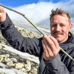 Archaeologist holding a 1,800-year-old bone-tipped arrow recovered from melting ice in Norway.