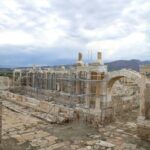 Wide view of the ancient Roman fountain at Tripolis, showing reconstructed columns, stone arches and restoration scaffolding.