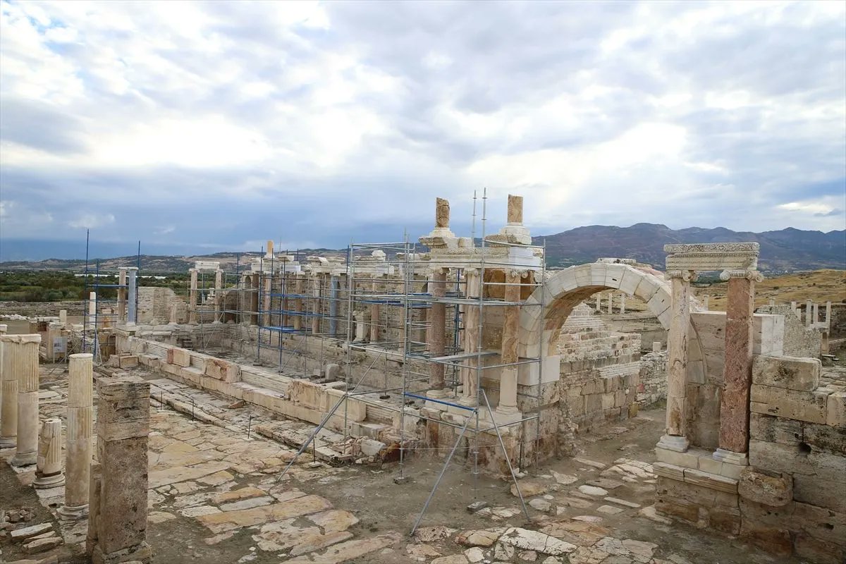 Wide view of the ancient Roman fountain at Tripolis, showing reconstructed columns, stone arches and restoration scaffolding.