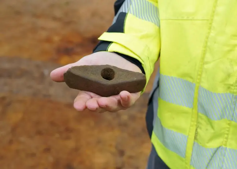 A 4,500-year-old perforated stone battle axe held in an archaeologist's hand during excavations in western Denmark.