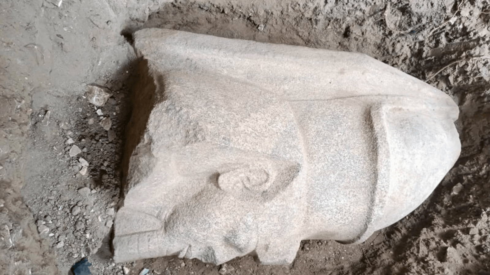 Close-up of the colossal Ramesses II statue head discovered in Egypt, showing the pharaoh's face and crown.