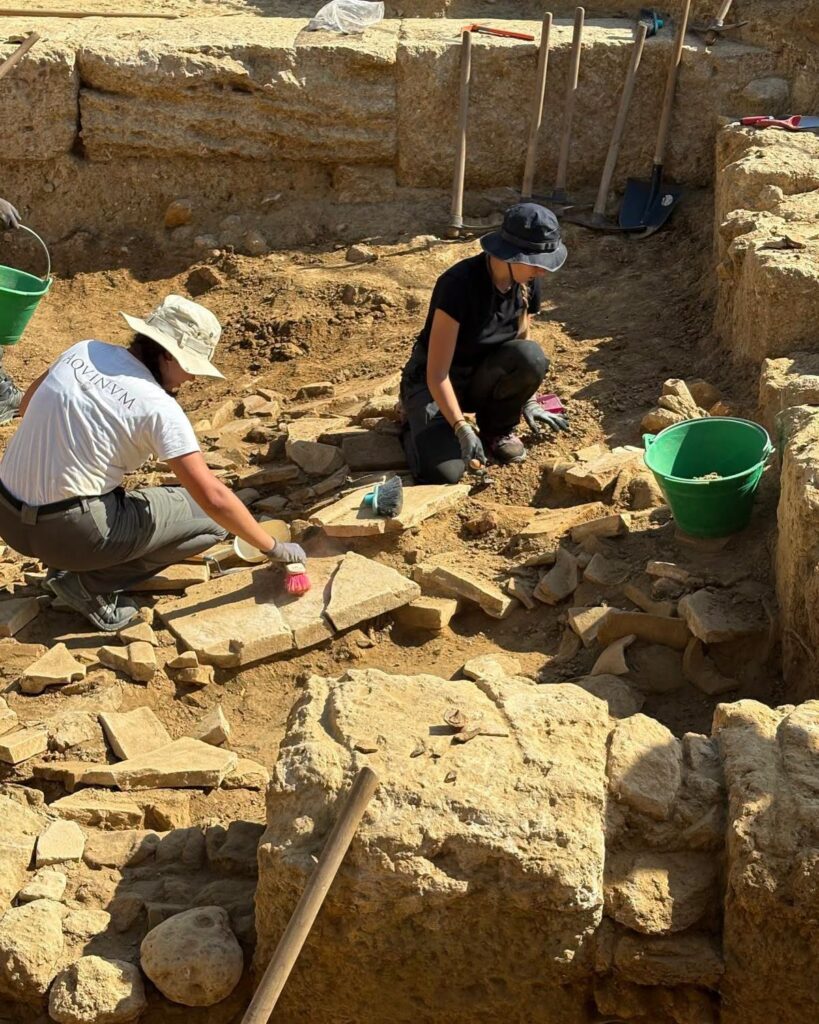 Two archaeologists cleaning ancient stone blocks at the Case Montana excavation site in Agrigento, Sicily.