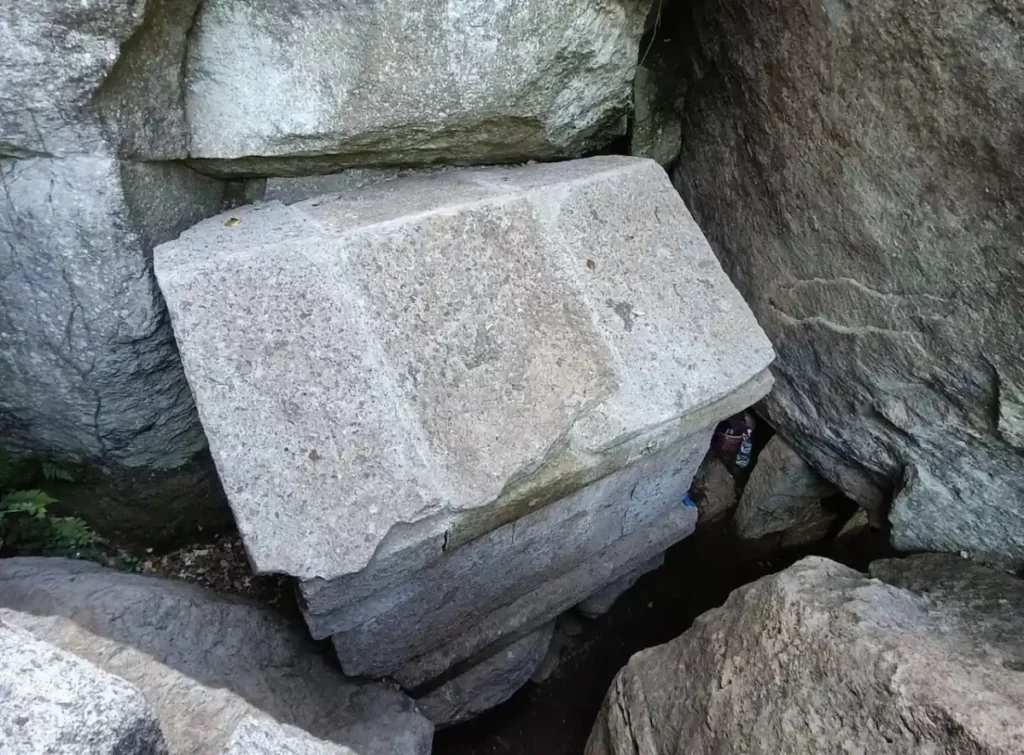 Ancient stone shrine with a pitched roof enclosed between enormous natural rock formations at Macchia delle Valli, Italy.