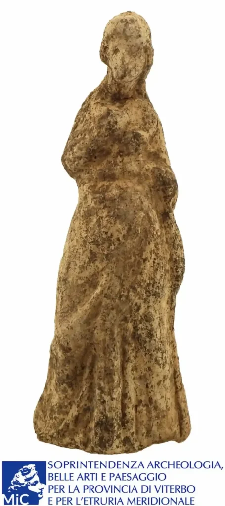 Ancient terracotta female figurine with a long robe and weathered facial features, discovered at the Sanctuary of Demeter near Vetralla.