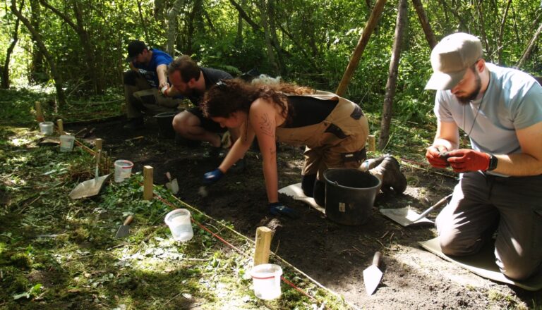 Archaeologists examining soil layers during excavations on wooded Cepurīte Island in Latvia.