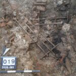 Ancient Roman iron window grille lying among stones and rubble during excavations at Augusta Raurica.