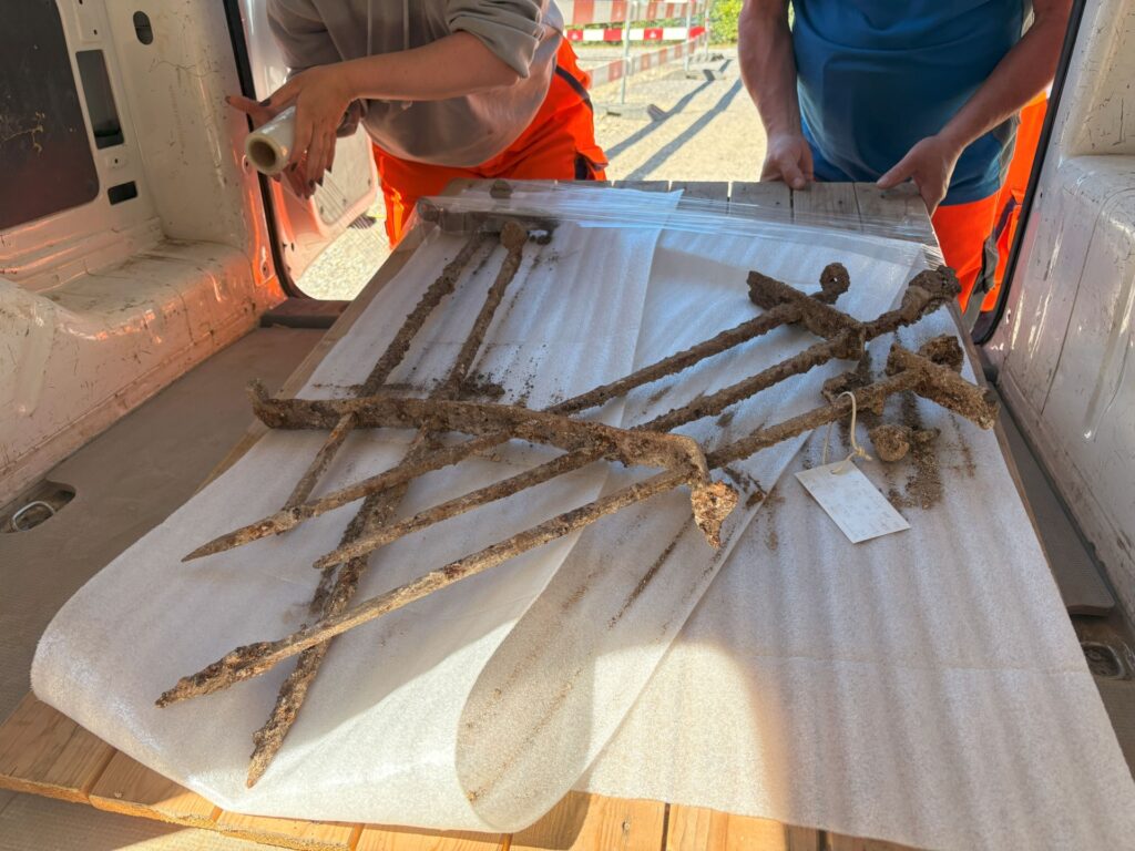 Excavation workers preparing a rare Roman iron window grille for transportation on protective padding.