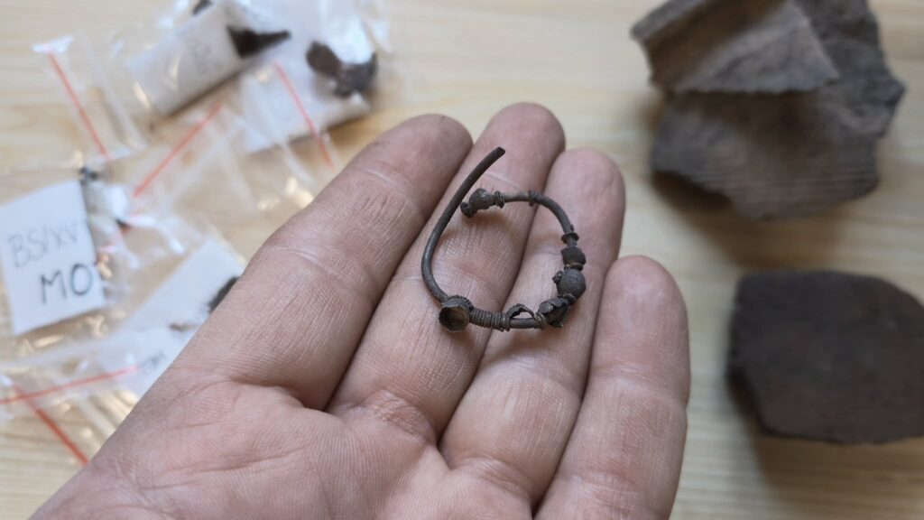 A silver temple ring (zausznica) decorated with beads and granulation, recovered from the Chodlik boat grave.
