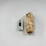 2,800-year-old bone flute from ancient Troy photographed beside an archaeological measuring scale.