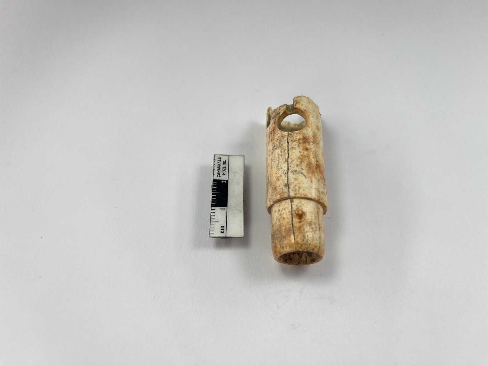 2,800-year-old bone flute from ancient Troy photographed beside an archaeological measuring scale.
