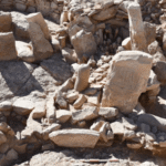 Excavated Neolithic shrine in Jordan with two upright stone figures surrounded by stone walls and archaeological remains.