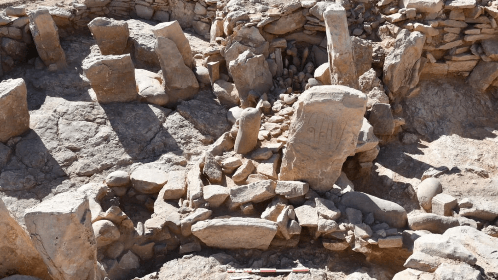 Excavated Neolithic shrine in Jordan with two upright stone figures surrounded by stone walls and archaeological remains.